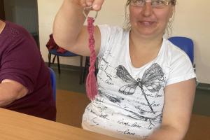 uczestniczka zajęć pozuje z breloczkiem zrobionej metodą makramy