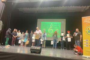 na oświetlonej scenie stoją wykonawcy piosenek z różnych Ośrodków. W tle na zielonym tle widać napis Trzynasty konkurs piosenki- Piosenka jest dobra na wszystko. 