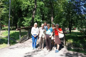 Sześć osób pozuje do zdjęcia, w tle znajduje się park, zielone drzewa oraz mostek