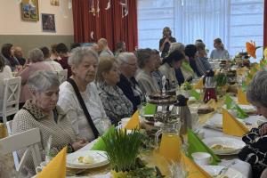 wielka, ustrojona sala. Przy stołach siedzą uczestnicy śniadania wielkanocnego