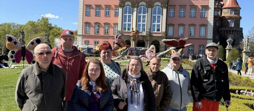 Na tle zamku stoi grupa zwiedzających. Pozują do zdjęcia.